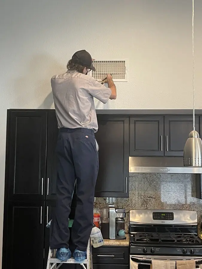 Technician inspecting an air vent during HVAC service in Gig Harbor
